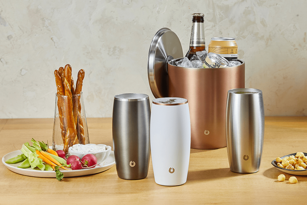 stainless steel beer cups on a table with snacks and a beer bottle in the background